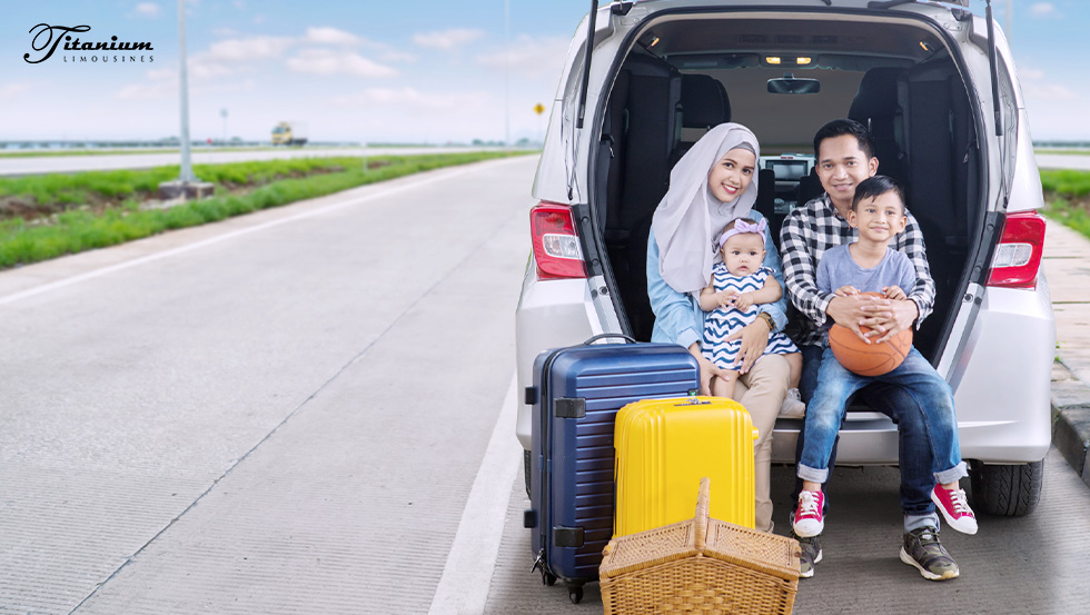 Happy family sitting on the trunk with their luggage by their feet